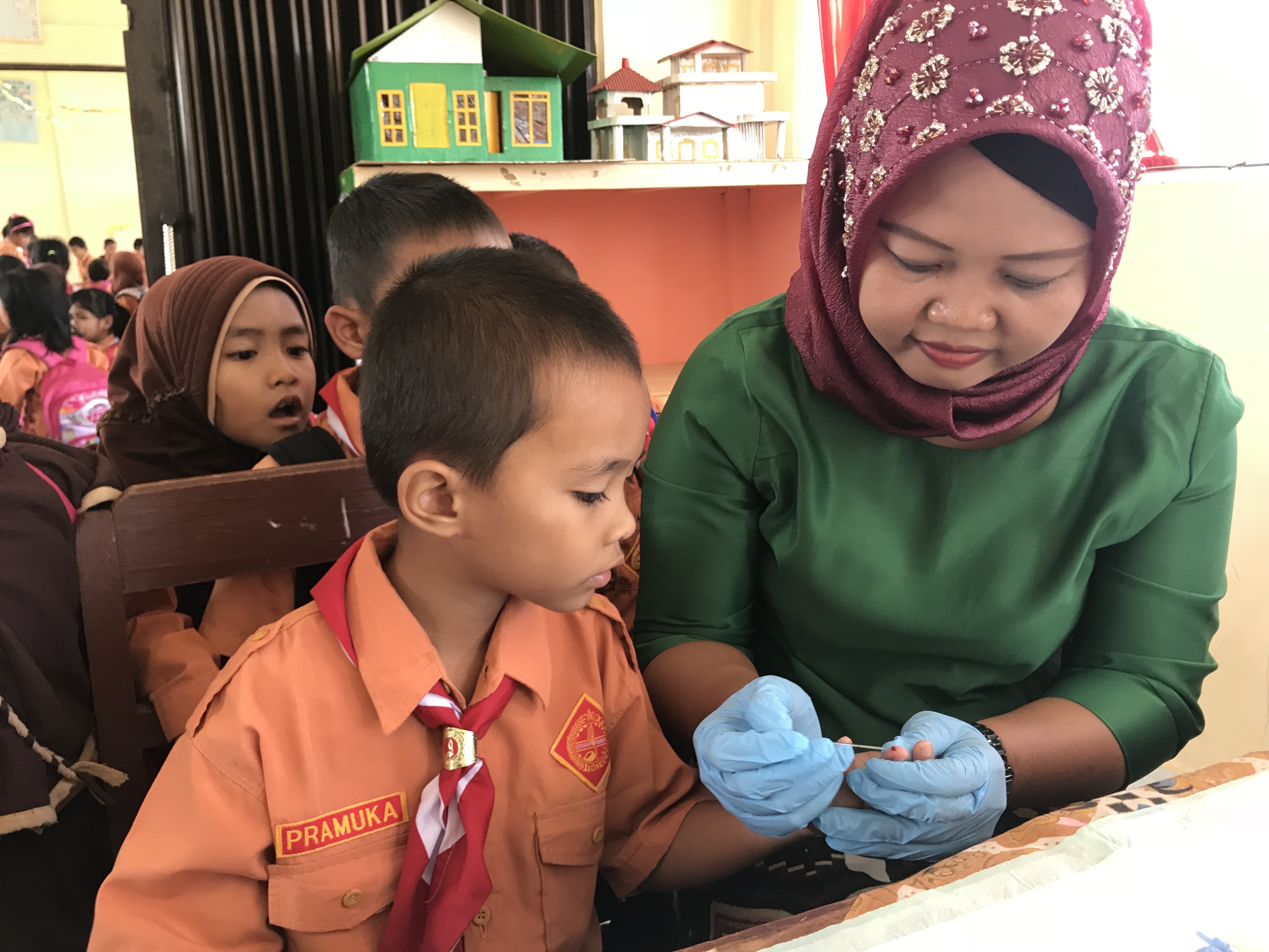 A young boy has his finger pricked during a transmission assessment survey in Indonesia. Photo credit: RTI International