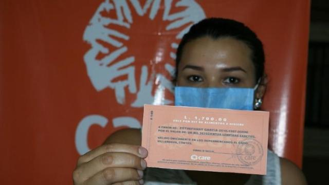 A woman from CARE's Honduras pilot voucher program holds a voucher for a supermarket.